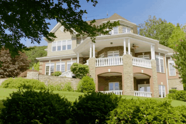 Large two-story house with expansive windows and a wraparound porch, showcasing how residential window tinting can preserve natural light while protecting interiors from UV damage.