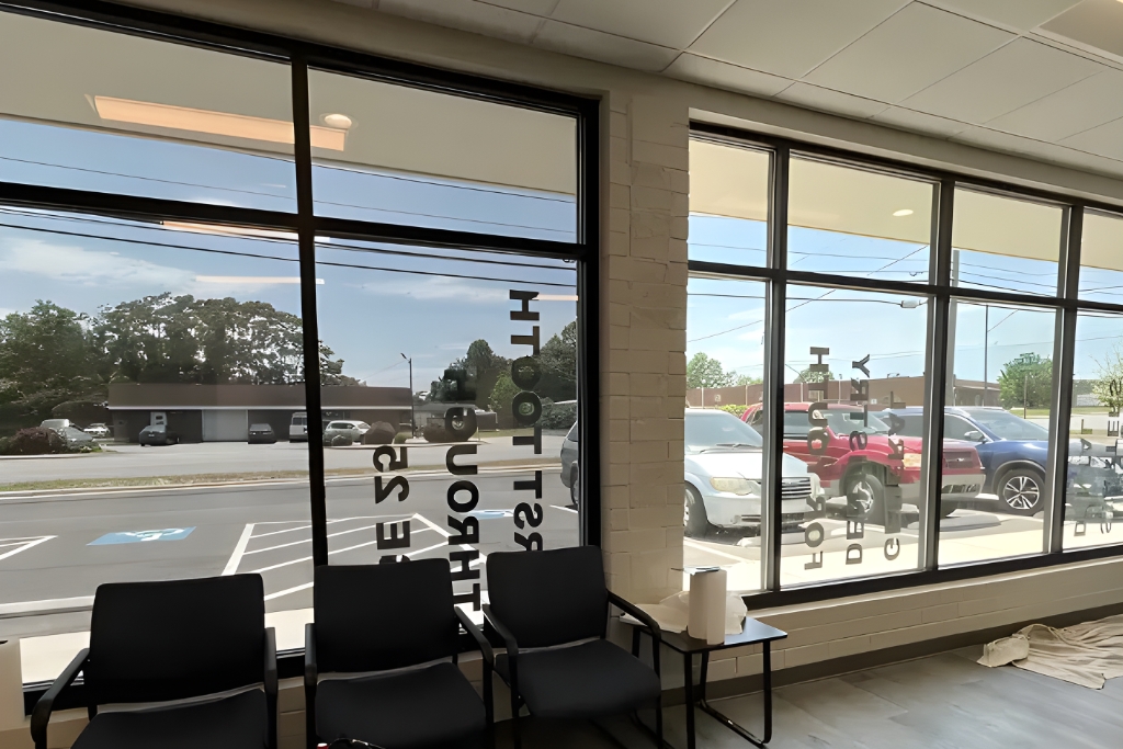 Interior view of a waiting area with large tinted windows showing reduced glare and reflective privacy film, demonstrating the energy-efficient and UV-protective benefits of residential window tinting.