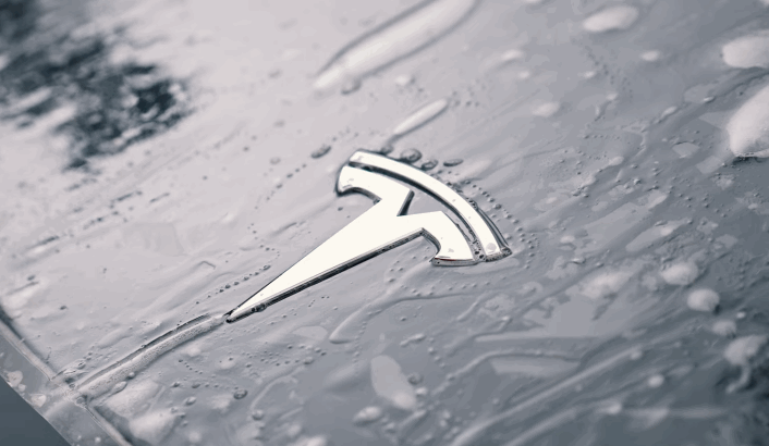 Close-up of a Tesla hood covered in water droplets, highlighting the smooth surface protected by paint protection film.