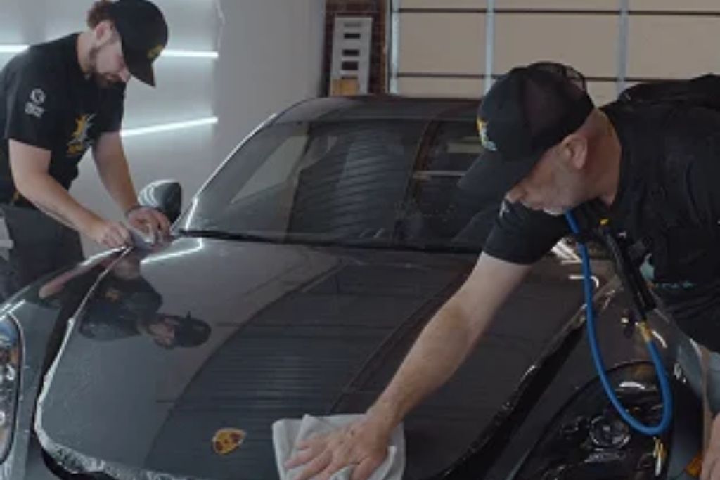 Sun-Kool technicians cleaning and preparing a black vehicle for paint protection film installation.