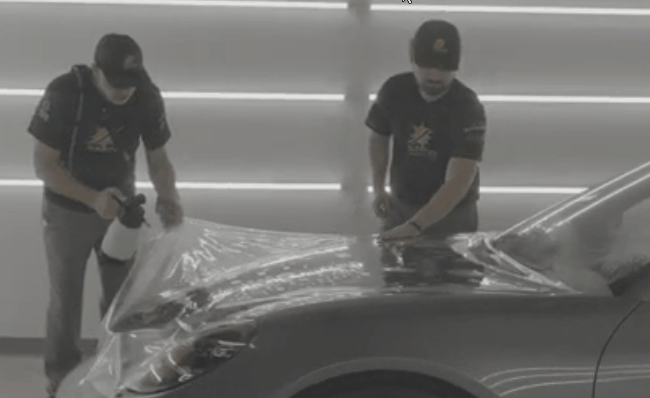 Sun-Kool technicians applying paint protection film to a vehicle hood.